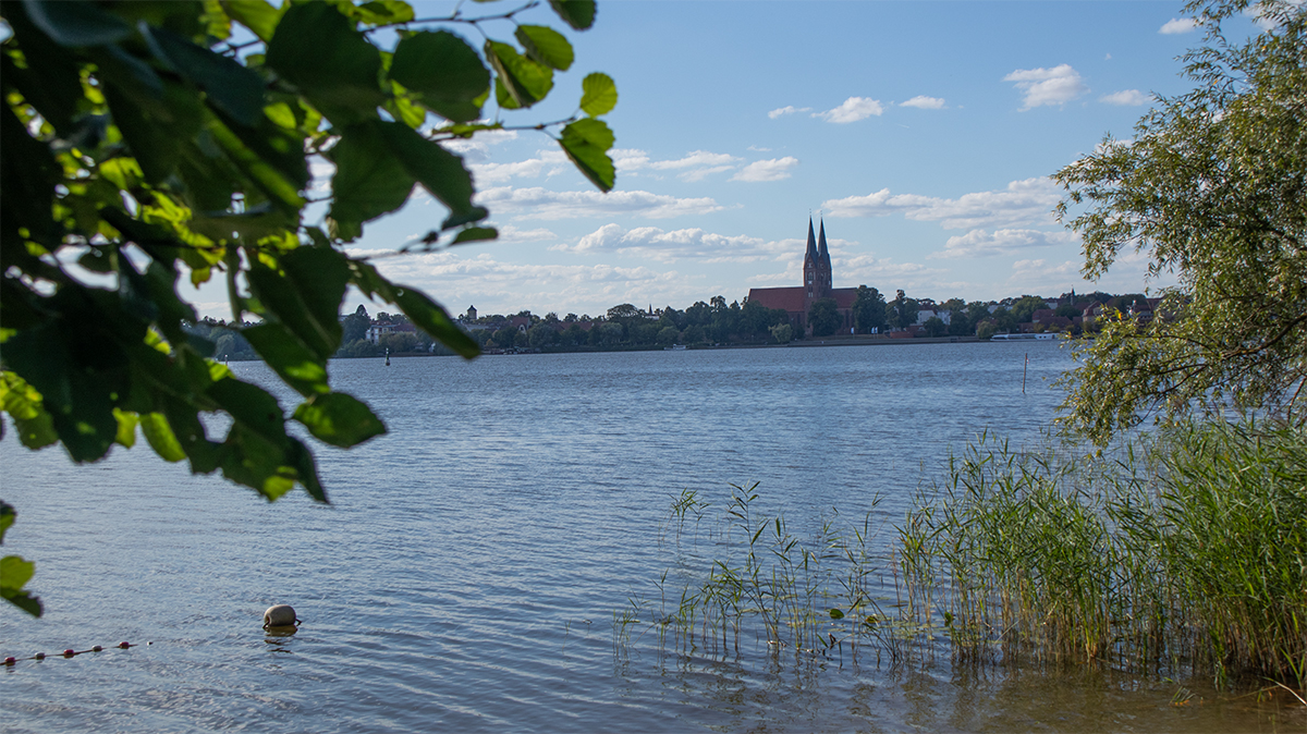 Pohled z koupacího místa u jezera Ruppiner See na Neuruppin s dvojicí věží klášterního kostela St. Trinitatis v pozadí.