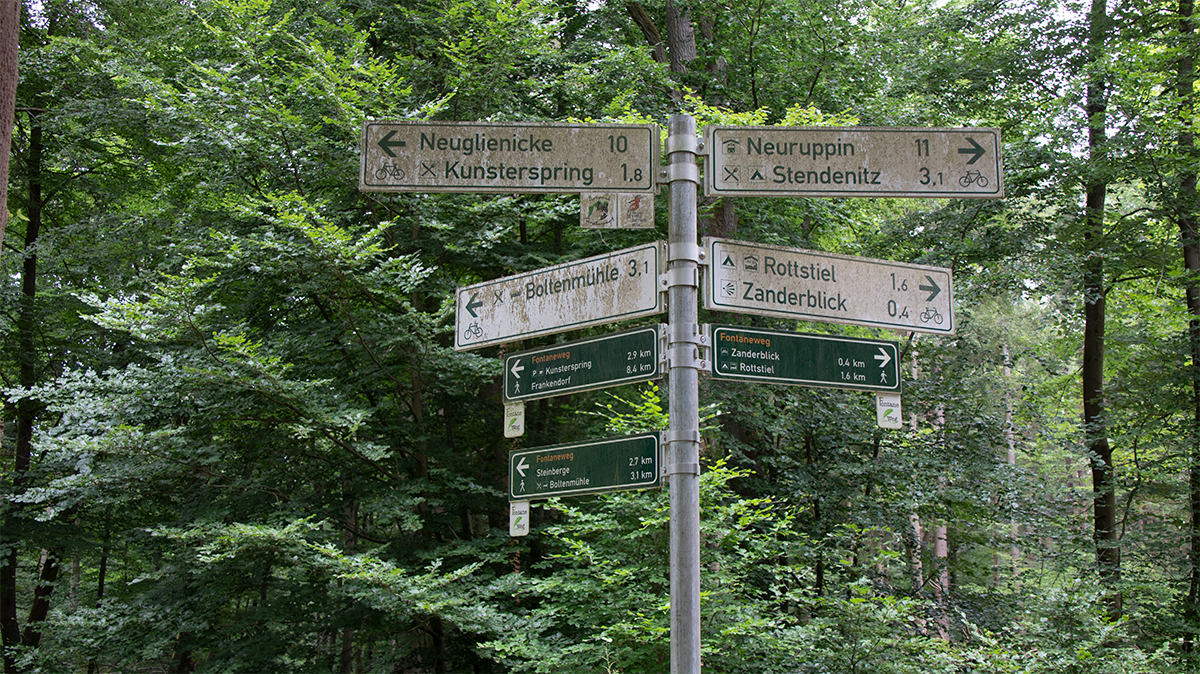53.0218267, 12.7893383 koordinatlarında Neuglienicke, Kunsterspring, Boltenmühle, Neuruppin, Stendenitz, Rottstiel ve Zanderblick yönlerine rota seçimi sunan yön levhası.